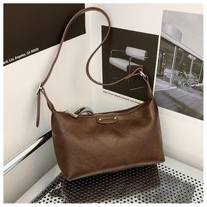 Detail of a brown quilted leather handbag with silver logo plate on industrial rack
