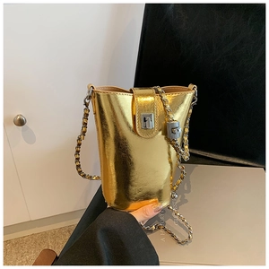 Détail du sac seau doré métallisé avec un fermoir rotatif argenté et une bandoulière chaîne