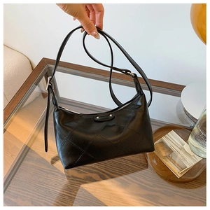 Detail of black quilted faux leather shoulder bag with adjustable strap and rivet accent