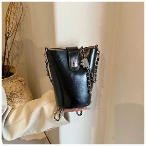 Détail du sac seau noir minimaliste avec bandoulière chaîne argentée et fermoir en métal