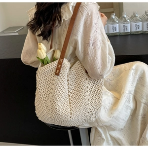 Close-up of off-white crochet tote bag with brown leather handles and knit texture