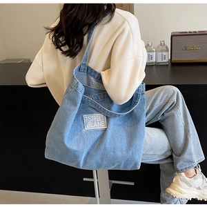 Detail showing high-capacity light blue denim tote bag with 7STREET 6LANE label