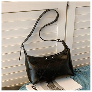 Detail of black glossy leather crossbody bag with quilted stitching and silver studs