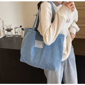 Detailed close-up of blue denim tote bag with 7STREET 6LANE woven label patch