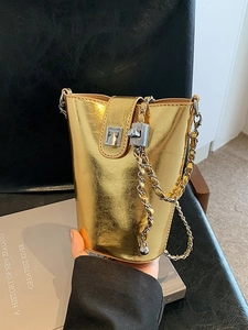 Sac seau doré métallisé avec bandoulière chaîne et fermoir sur fond de studio élégant