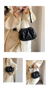 Close-up of black glossy pleated cloud bag with silver drawstring beads and chain strap