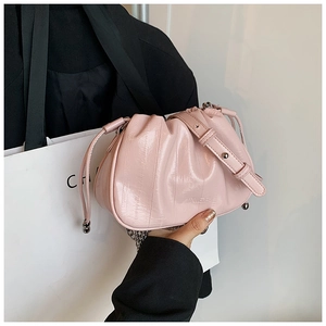 Detail of light pink ruched cloud bag showing glossy pleated texture and slim strap