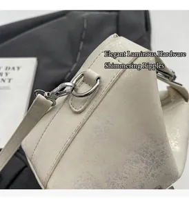 Detail of silver-tone metal hook and shimmering ivory textured leather on bucket bag