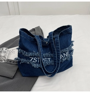 Vue détaillée du sac en jean bleu foncé avec bords effilochés et broderie 7STREET LANE