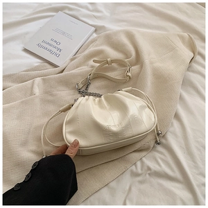 Close-up of cream white pleated cloud bag with metallic chain and AINIER logo detailing