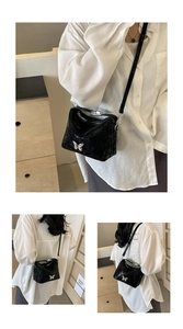 Detailed views of a black textured bucket bag with a silver butterfly ornament and strap