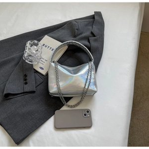 Detail view of silver laser metallic crossbody bag with chain on grey blazer