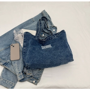 Flat lay of deep blue denim tote bag with text label on a clean white background