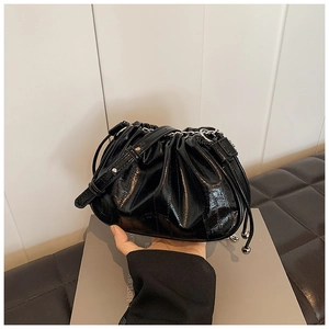 Detail of black patent leather cloud bag with ruched texture and silver chain strap