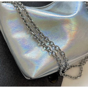 Detail of silver holographic handbag showing wrinkled texture and metallic chain strap