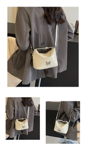 Detail of glossy cream leather crossbody bag with elegant silver butterfly clasp