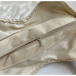 Close-up of beige woven bag inner lining with smooth metal zipper and neat stitching
