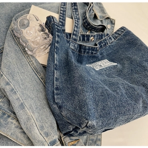 Detail shot of navy denim tote bag with 7 STREET ISLAND patch and metal snap button