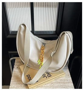 Détail du sac hobo avec bandoulière tressée et tirette de zip orange vif