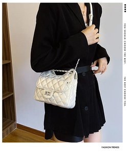 Détail du sac matelassé blanc avec boucle argentée porté sur une veste noire