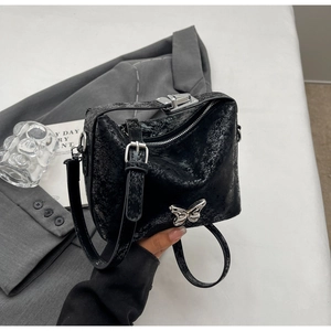 Detail of black vintage leather bucket bag with silver butterfly metal logo