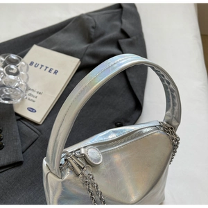 Macro shot of silver holographic handbag with metallic texture and decorative chain