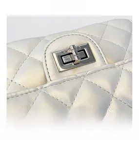 Détail du fermoir rotatif argenté sur un sac matelassé blanc en cuir véritable