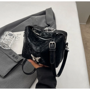 Close-up of black crackle textured bucket bag with silver butterfly metal detail