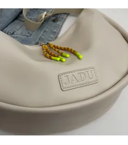 Détail du sac hobo beige avec logo JADU et tirette de zip en corde vert citron