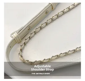 Détail de la bandoulière en cuir réglable et de la chaîne en métal sur un sac beige