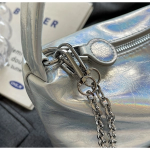 Close-up of silver laser shoulder bag detailing pleated texture and metallic hardware
