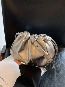 Silver metallic pleated cloud bag with leather strap and drawstring in urban setting