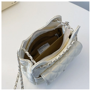 Vue détaillée du sac matelassé blanc montrant la poche zippée et l'étiquette de marque