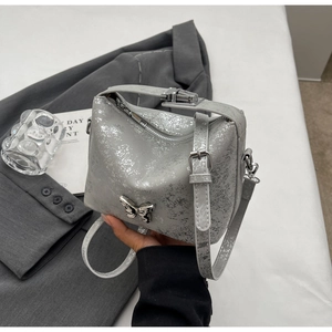 Close-up of silver cracked texture bucket bag with 3D metal butterfly accent