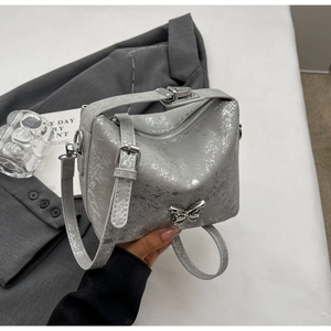 Detail of silver bucket bag featuring 3D butterfly buckle and marble splash texture