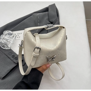 Detailed macro of cream faux leather bucket bag texture with silver butterfly ornament