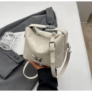 Detail of the pearlescent bucket bag featuring a silver butterfly clasp and cracked texture