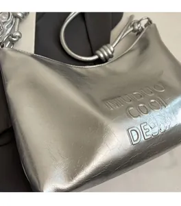 Detail of silver metallic tote bag featuring pleated texture and embossed logo