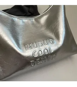 Close-up of silver tote bag with textured metallic finish and embossed Muduo logo