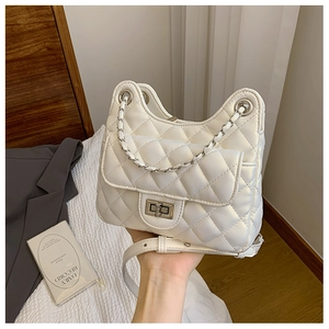 Gros plan sur le sac matelassé beige avec fermoir rotatif argenté et bandoulière chaîne