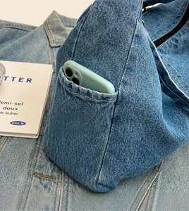 Detail van blauwe denim crossbodytas met zijvak en mobiele telefoon voor functionaliteit