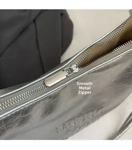 Detail shot of smooth silver metal zipper and wrinkled metallic texture on tote bag