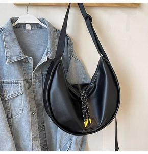 Détail du sac croissant noir avec tirette de fermeture tressée et accents jaunes