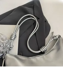 Detailed close-up of knotted shoulder strap on a silver metallic faux leather tote bag