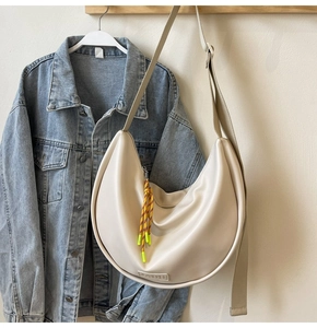 Détail du sac hobo crème avec fermeture éclair en corde tressée et logo de la marque