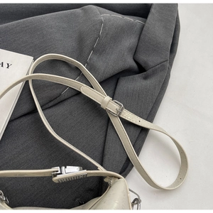 Detail of adjustable cream leather strap with silver buckle on a stylish bucket bag