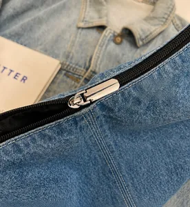 Macro-opname van de gladde zilveren metalen rits op een blauwe denim schoudertas