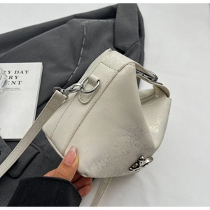 Detailed texture of white distressed leather bucket bag with silver metal buckle on grey blazer