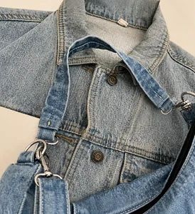 Detailopname van blauwe denim crossbodytas met zilveren metalen haken en stoftextuur