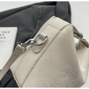 Close-up of ivory bucket bag showing cracked texture and silver metal hardware details